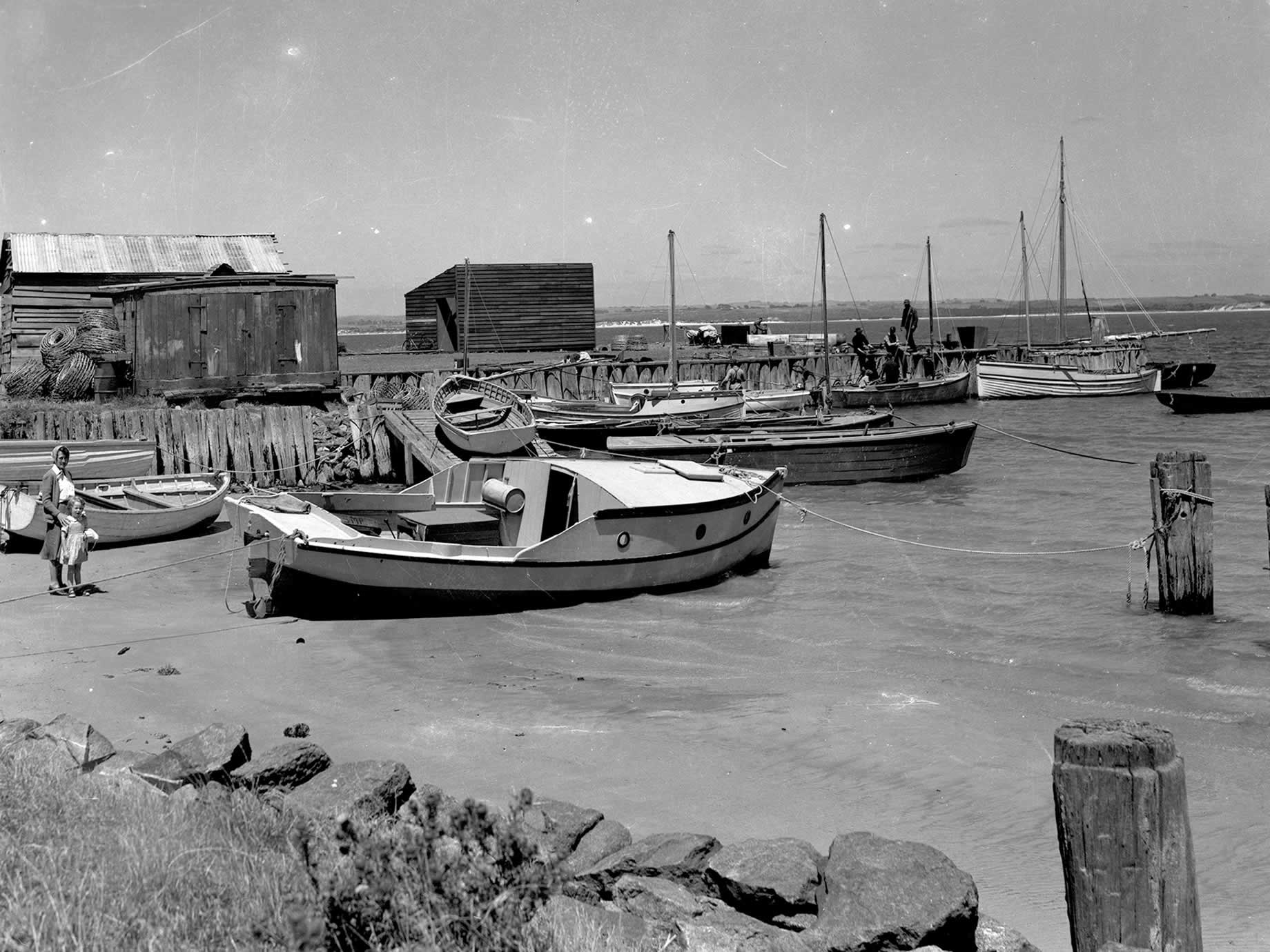 Mehrere festgemachte Fischerboote an der alten Anlegestelle mit kleineren Booten im Vordergrund